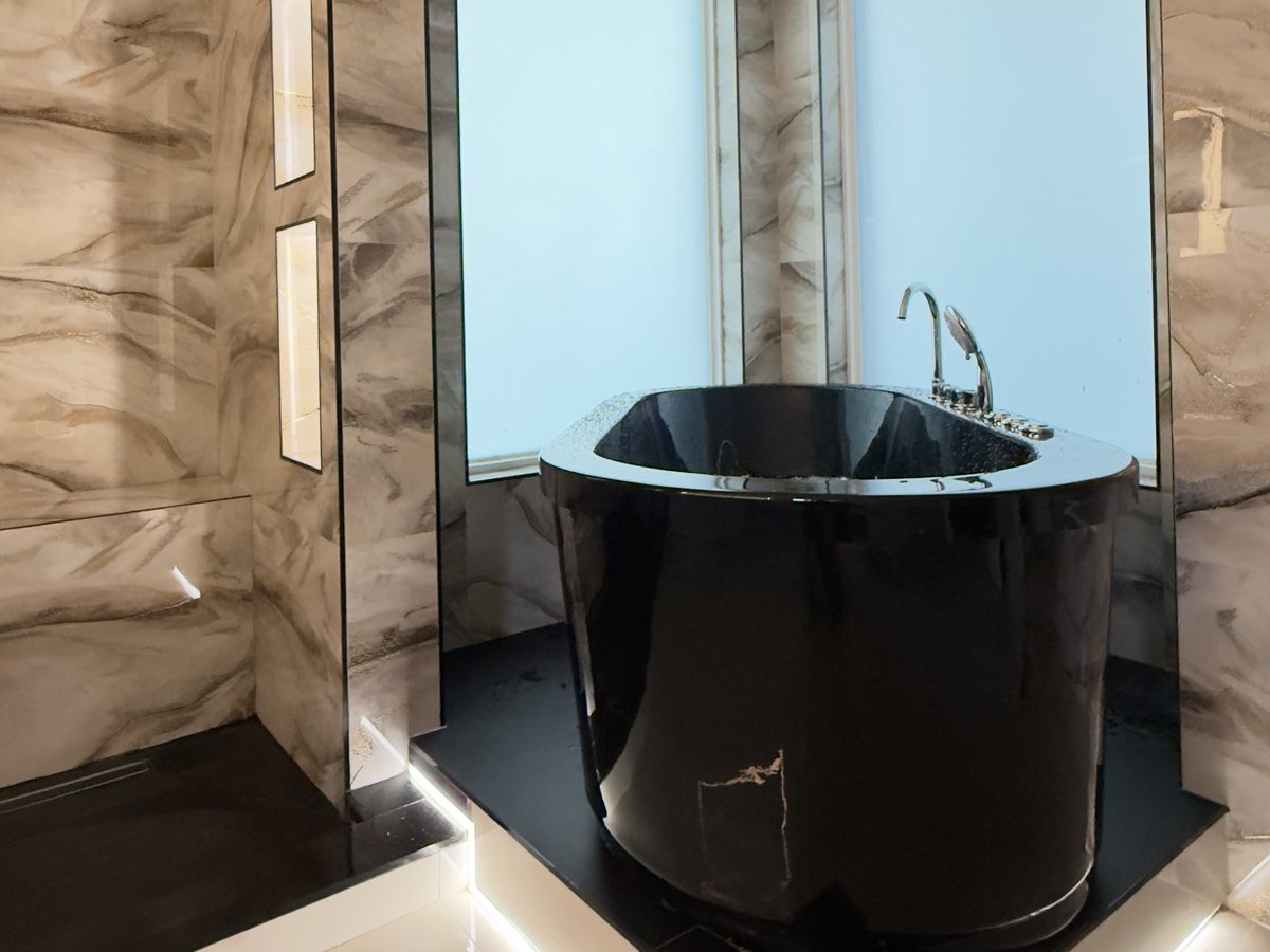 Freestanding black soaking tub beneath a crystal chandelier, South Florida bathroom remodel