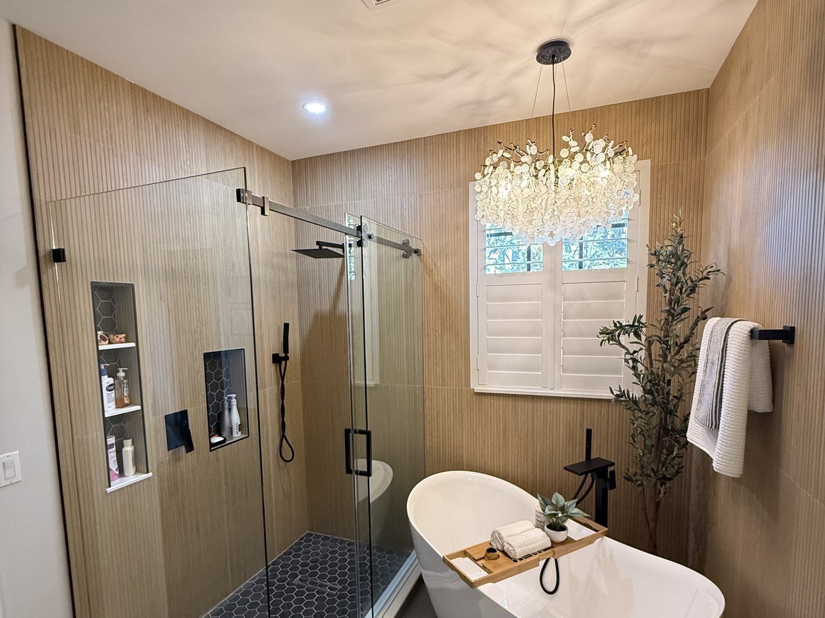 Spa-style bathroom with wood-slat accent wall and freestanding tub